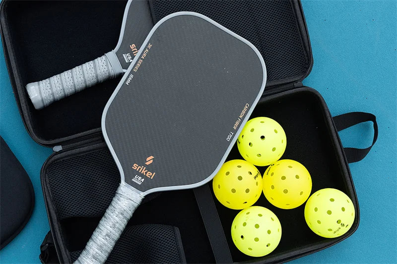 Two pickleball paddles and six yellow perforated pickleballs in a black carrying case.