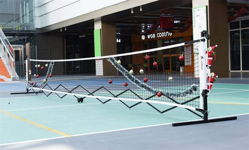 A pickleball net decorated with Christmas ornaments and tinsel.