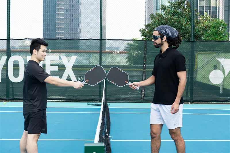 two men holding the pickleball paddles contact each other to show their friendliness and respect