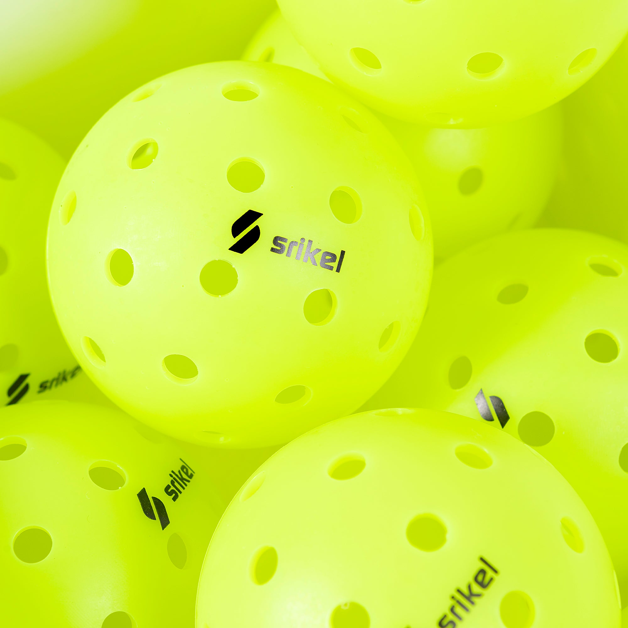 Multiple green Strikel XS-40 Outdoor Pickleball Balls are grouped together